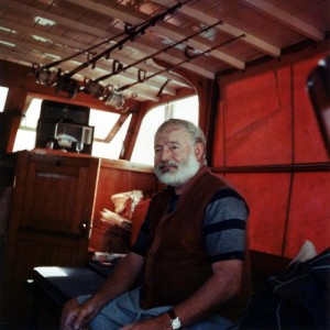 Ernest Hemingway in the cabin of his boat El Pilar. Around his wrist probably an 18c golden, leather band Rolex Oyster from the 1950s